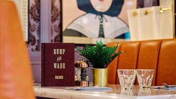 A table with a book titled 'Rump and Wade', a small potted plant, and two glasses.