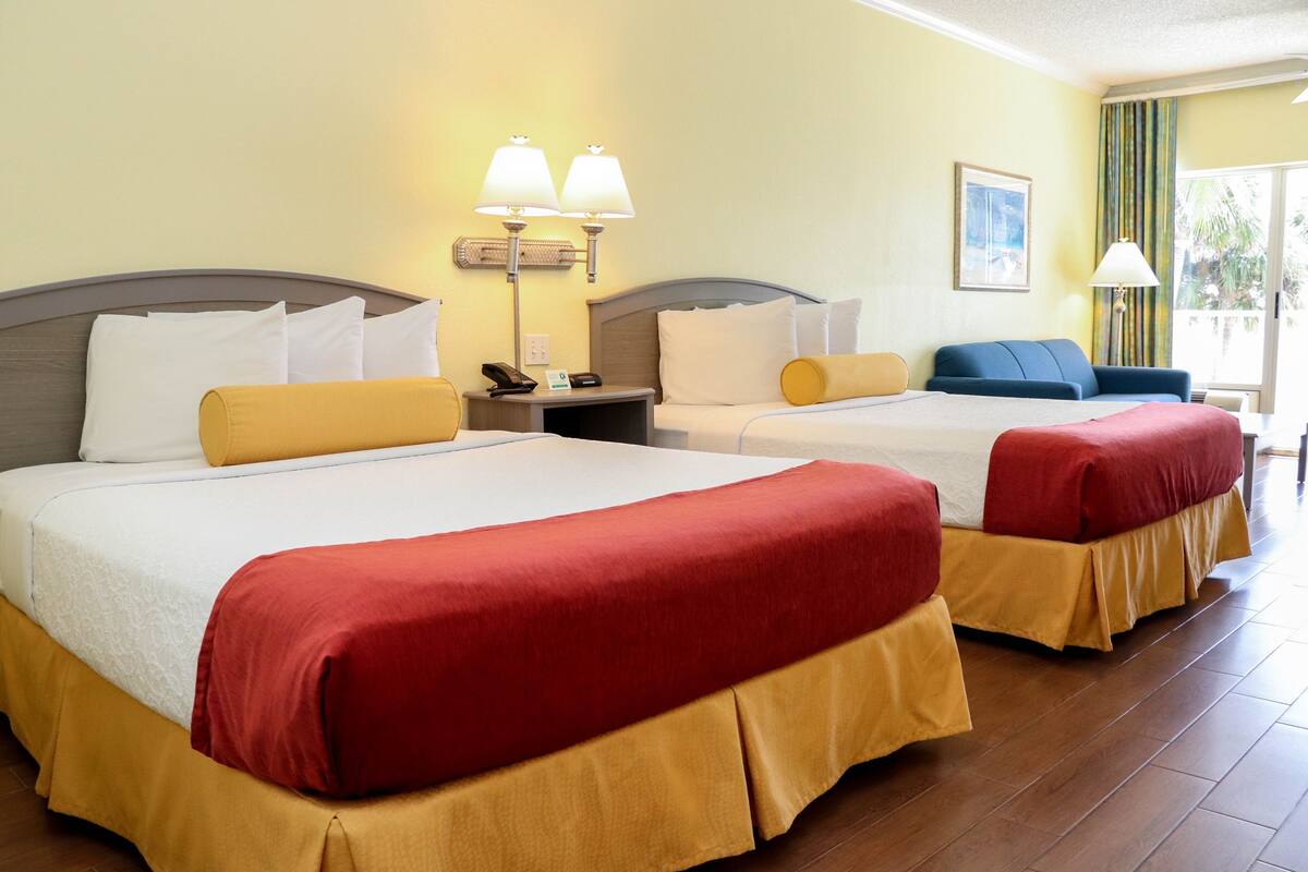 A hotel room with two beds, a nightstand with a phone, and a window with curtains.