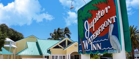 A hotel sign with a tropical theme, featuring a pelican and palm trees.