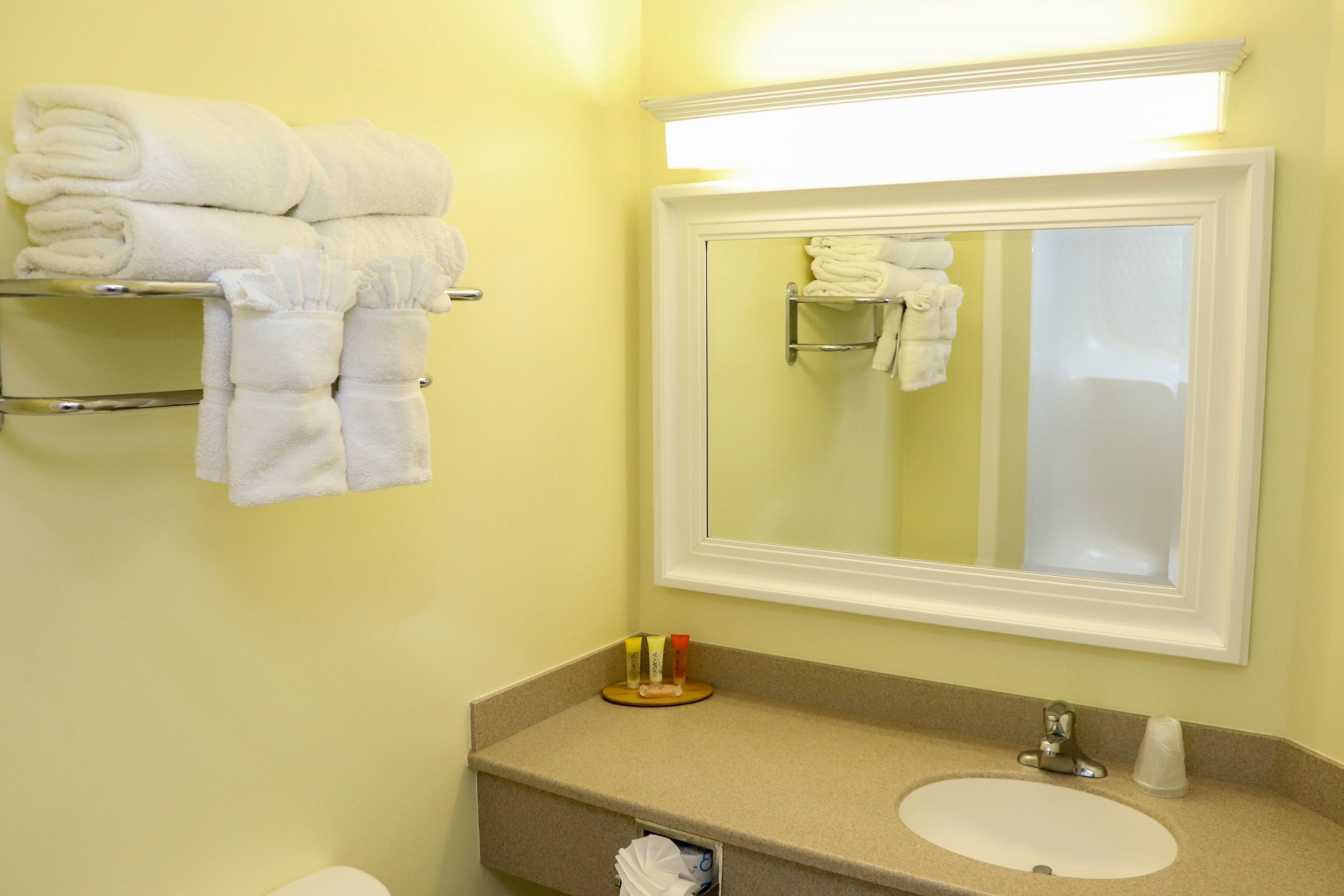 A bathroom with a sink, mirror, and towel rack.