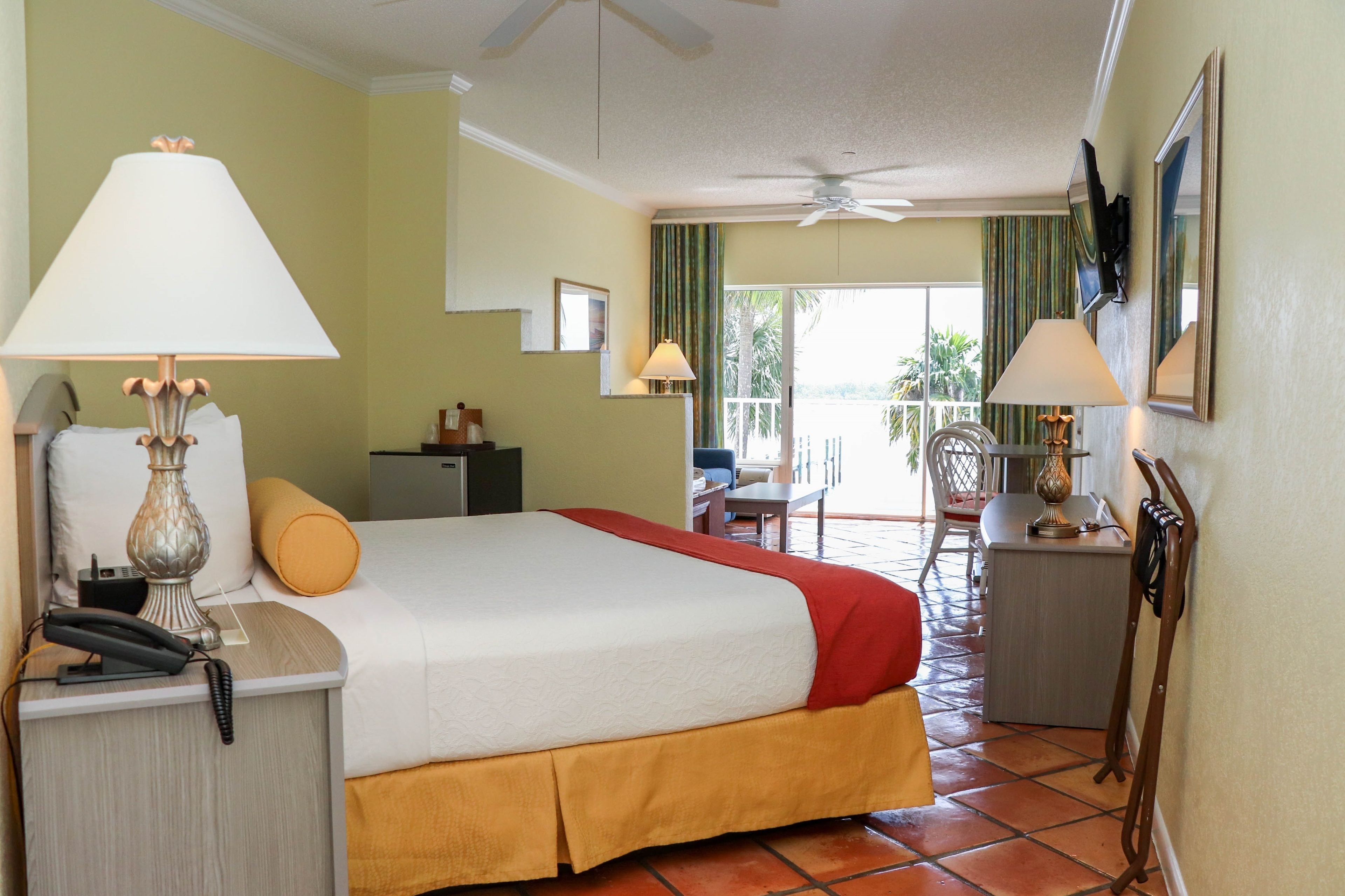 Habitación de hotel con cama, escritorio, silla y balcón con vistas.