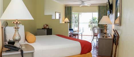Habitación de hotel con cama, escritorio, silla y balcón con vistas.