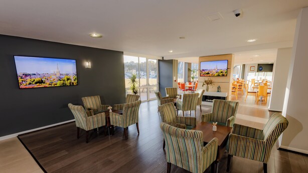 A spacious dining area with striped chairs and a large flat-screen TV mounted on the wall. - Holiday Inn Express Norwich by IHG (Norwich)