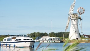A traditional windmill by a calm river with boats docked nearby. - Holiday Inn Express Norwich by IHG (Norwich)