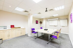 A conference room with a white table, purple chairs, a projector, and a whiteboard. - Holiday Inn Express Norwich by IHG (Norwich)