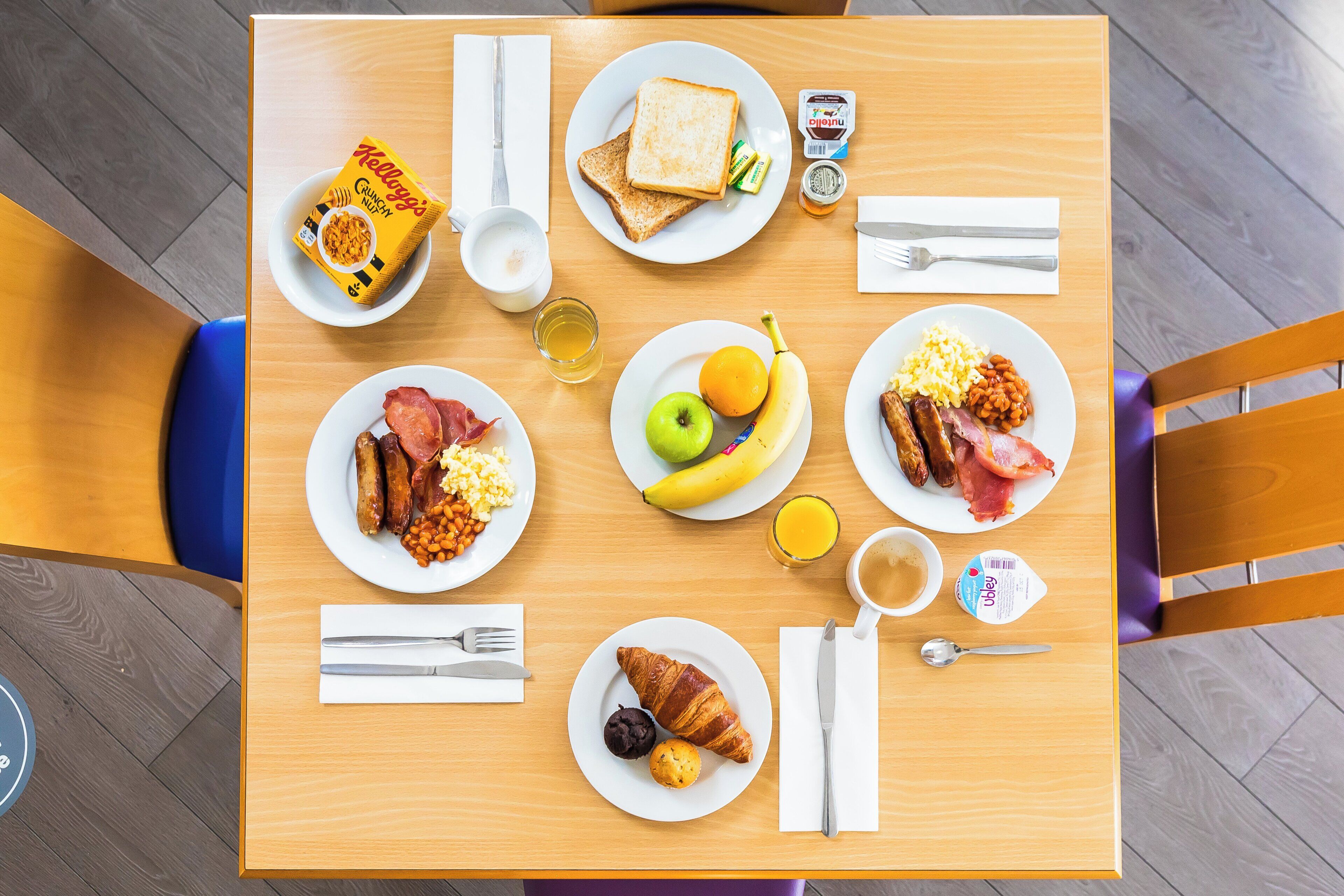 Ett frukostbord med tallrikar fyllda med mat, en kaffekopp och ett glas juice.