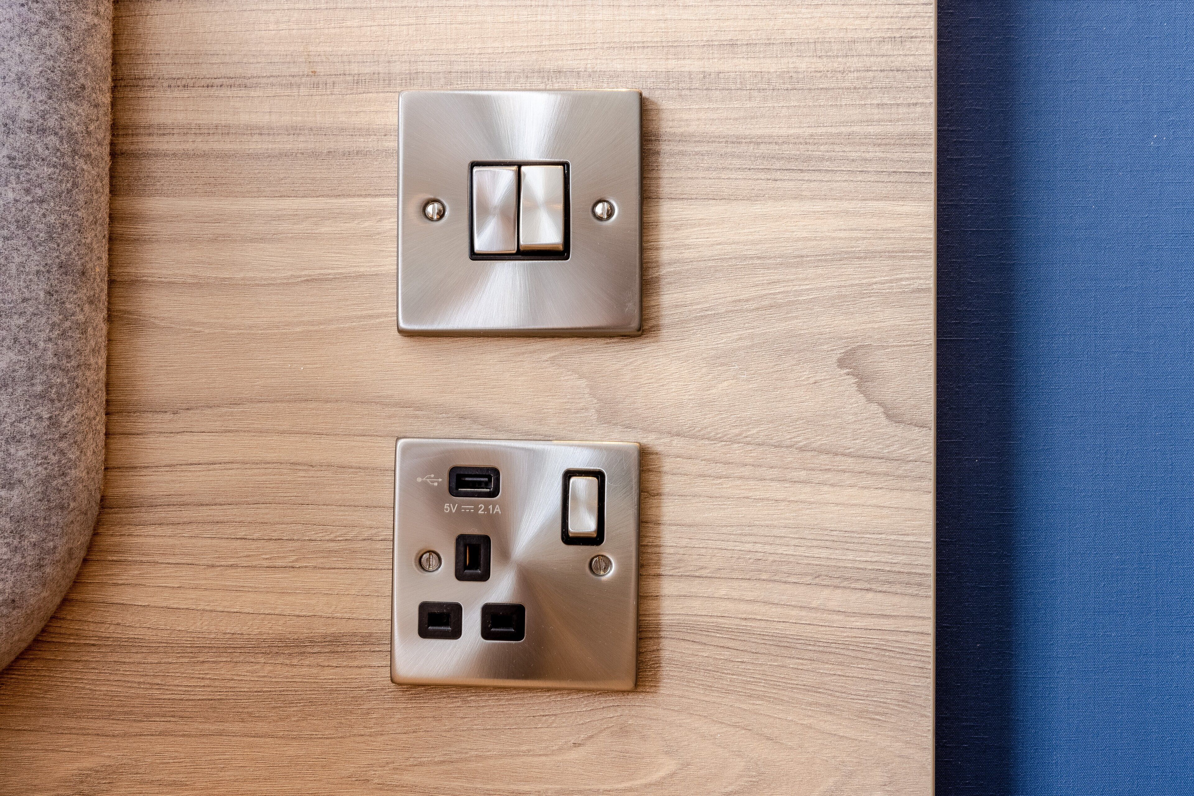 Toma corriente empotrada en la pared con interruptor y puertos USB sobre una superficie de madera.