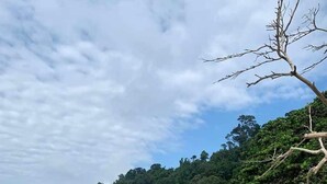 A beach with clear turquoise water, sandy shore, and a forested hill in the background. - Ascott Gurney Penang (George Town)