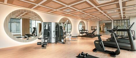 A gym with exercise equipment, wooden floors, and large mirrors.
