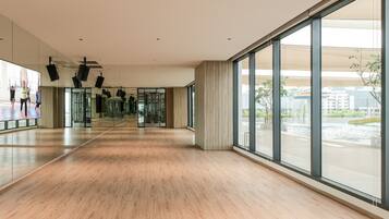 A spacious, modern interior with large windows, a wooden floor, and a mirrored wall.
