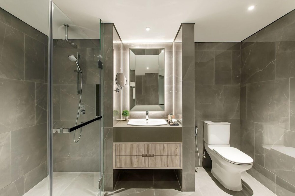 A modern bathroom with a glass shower enclosure, a sink with a mirror above it, and a toilet.