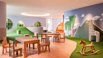 Un área de juegos infantiles con mesas, sillas y un caballo balancín.