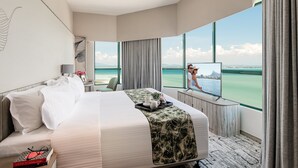 A hotel room with a large bed, a TV, a desk, and a view of the ocean. - Ascott Gurney Penang (George Town)