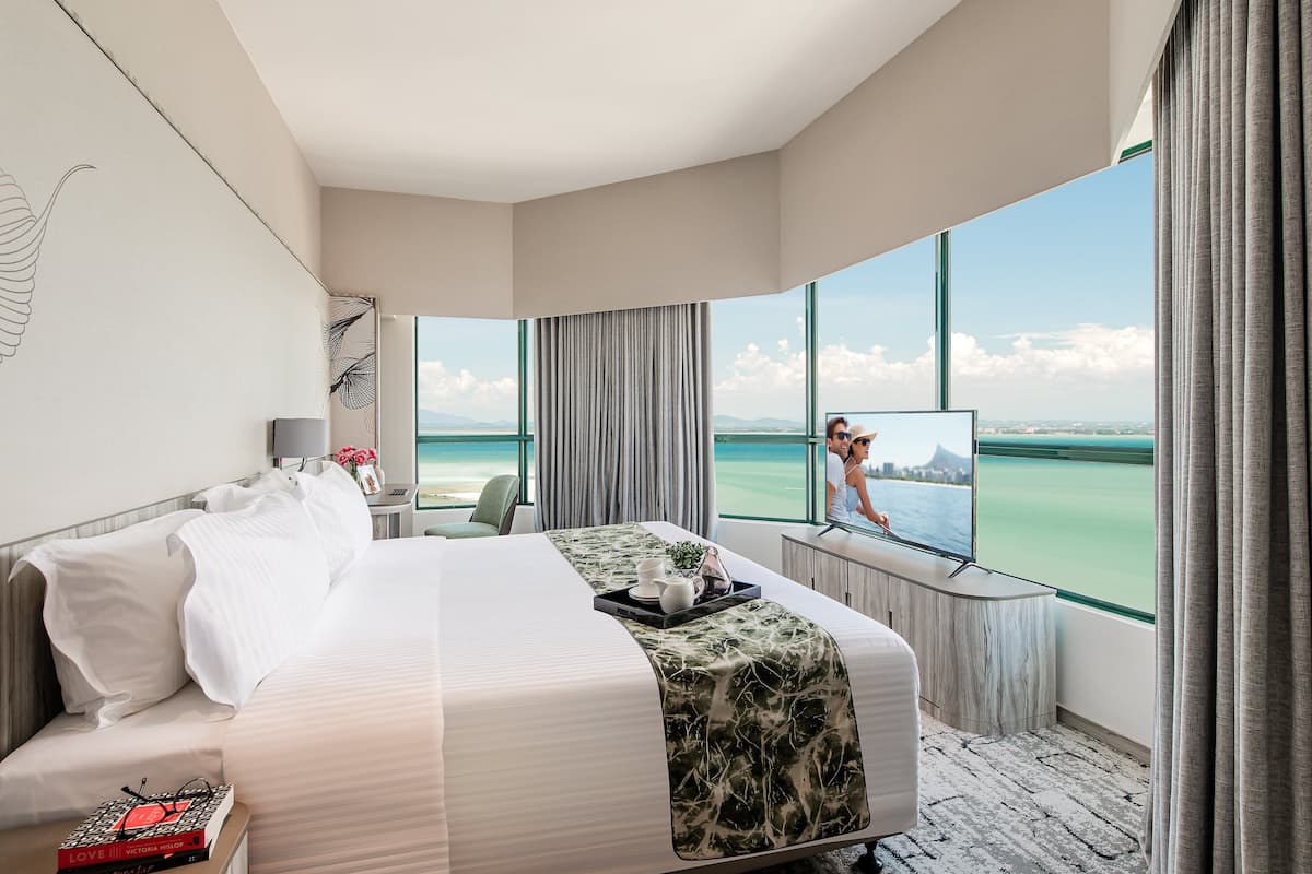 Habitación de hotel con una cama grande, televisión, escritorio y vista al océano.
