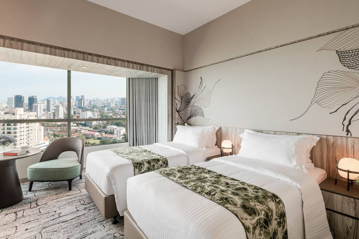 Habitación de hotel con dos camas, vistas de la ciudad, una silla y un escritorio.