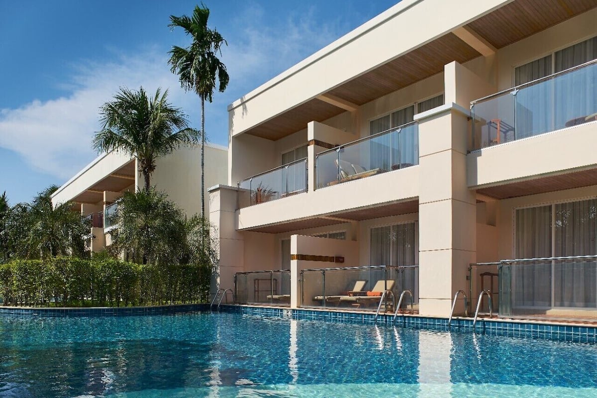 Un hôtel moderne doté d’une piscine, de balcons et de palmiers.