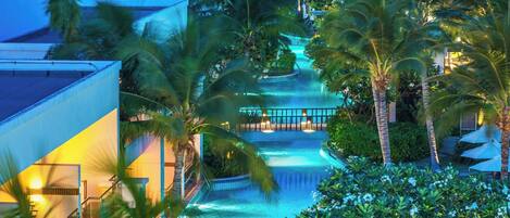 A resort with a water feature, palm trees, and a view of the ocean.