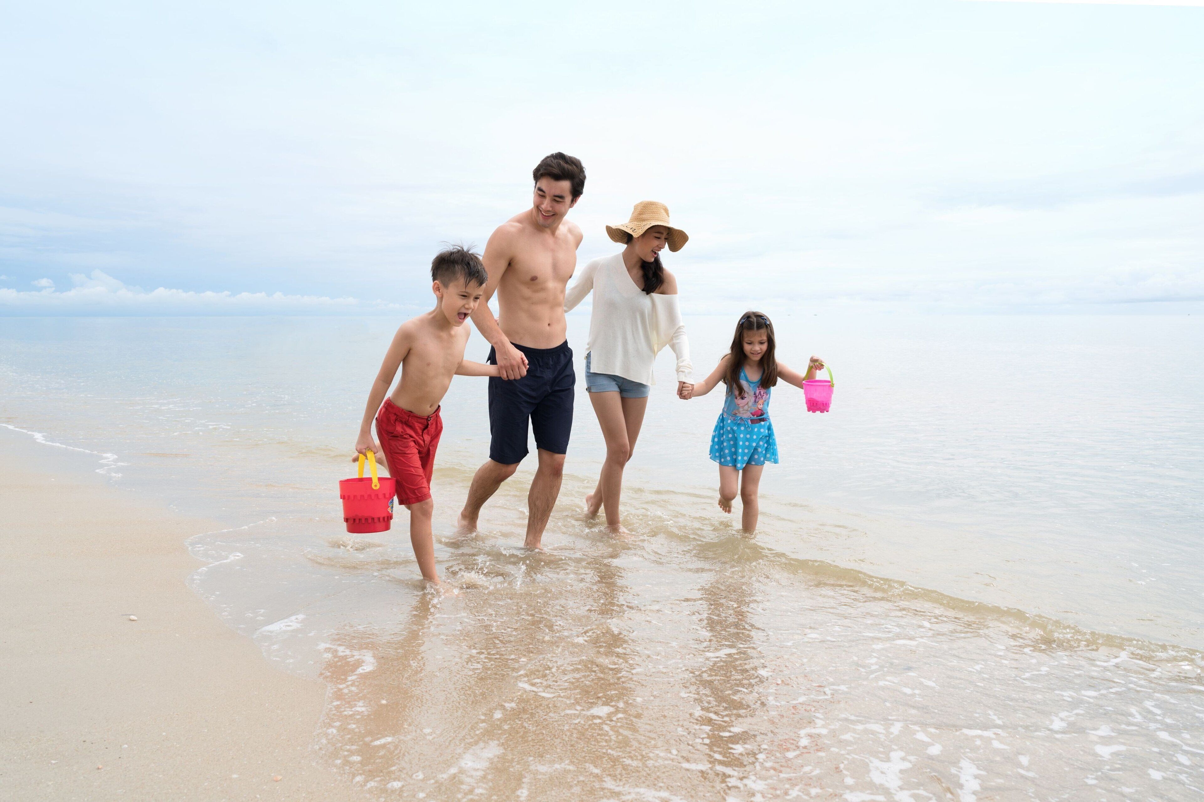 A family walking on a beach with clear skies.