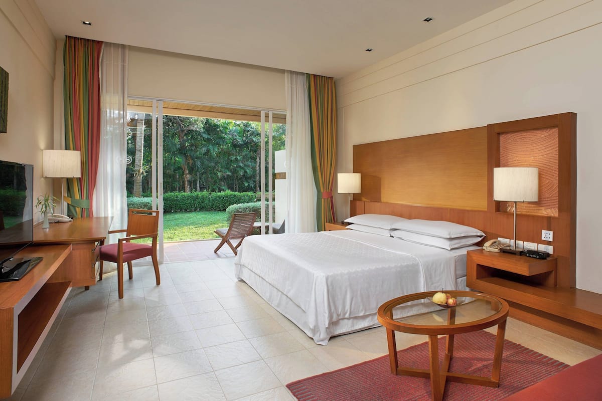 Une chambre d’hôtel avec un lit, un bureau, une chaise et une petite table sur laquelle se trouvent des fruits.