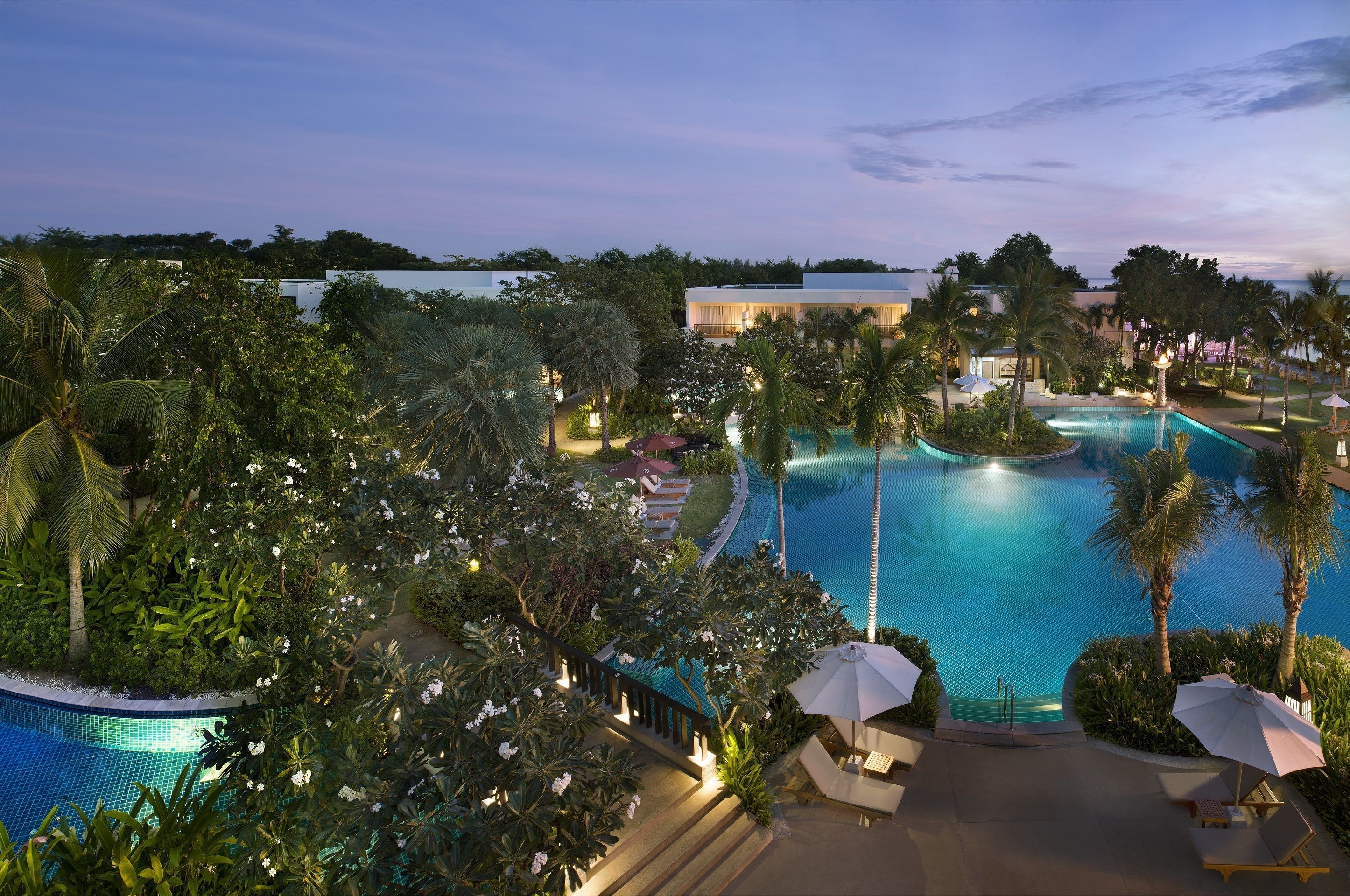 A resort pool area with a clear view of the pool, lounge chairs, and surrounding greenery.