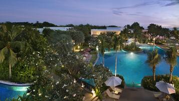A resort pool area with a clear view of the pool, lounge chairs, and surrounding greenery.