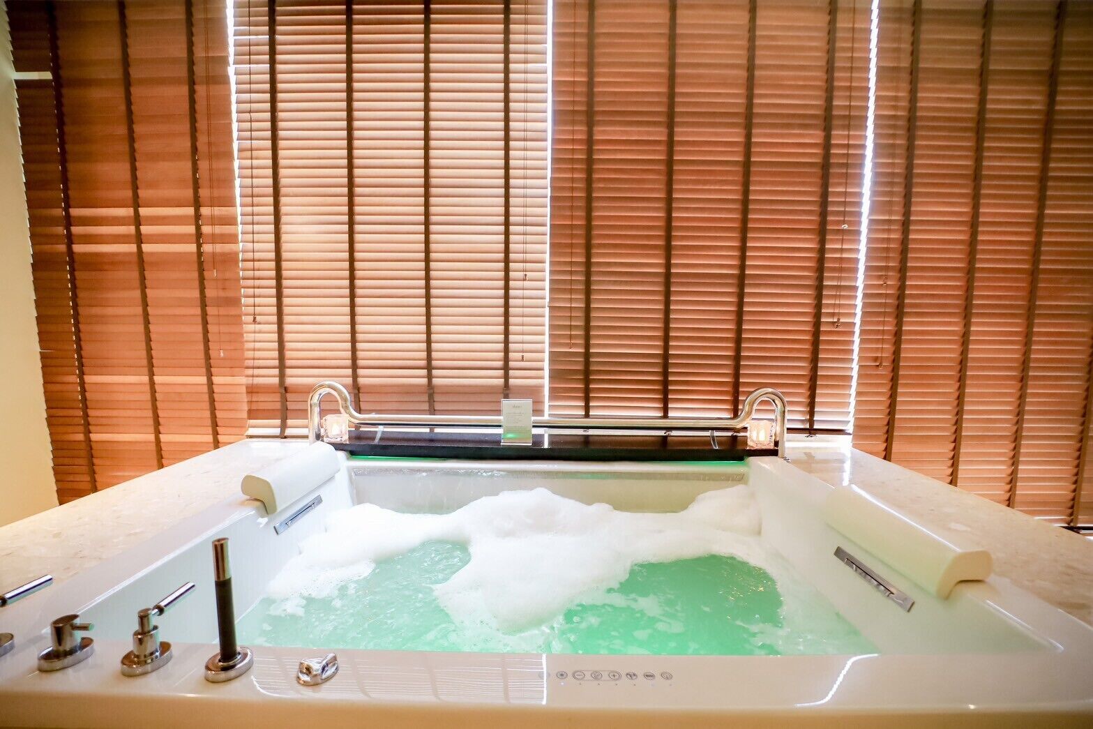 A bathtub with a greenish water feature, a faucet, and a control panel.
