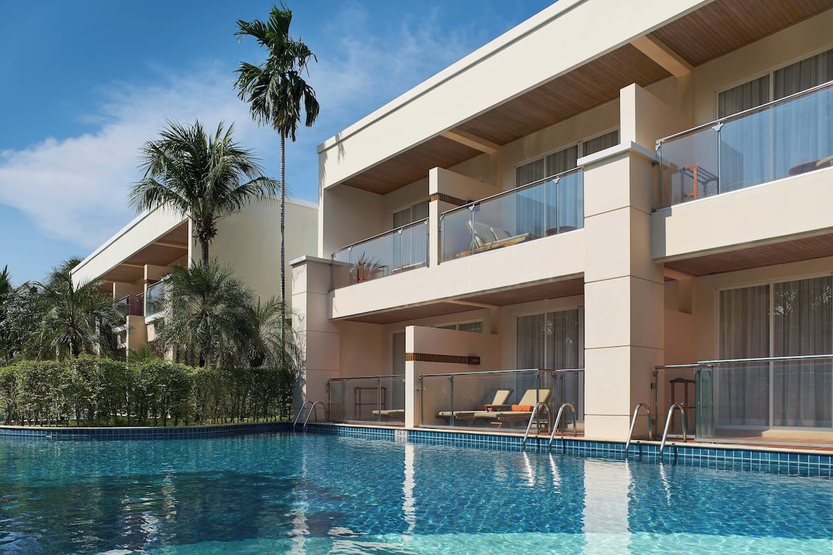 Un hôtel doté d’une piscine, de plusieurs balcons et de palmiers.