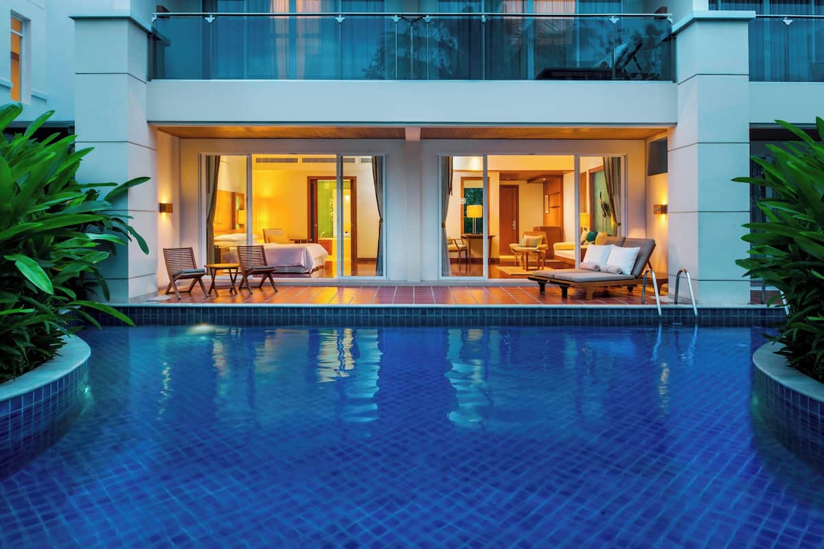 Un hôtel moderne doté d’une piscine, d’un espace extérieur aménagé et d’une entrée bien éclairée.