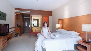 A hotel room with a bed, a TV, a desk, and a bathroom visible through an open door.