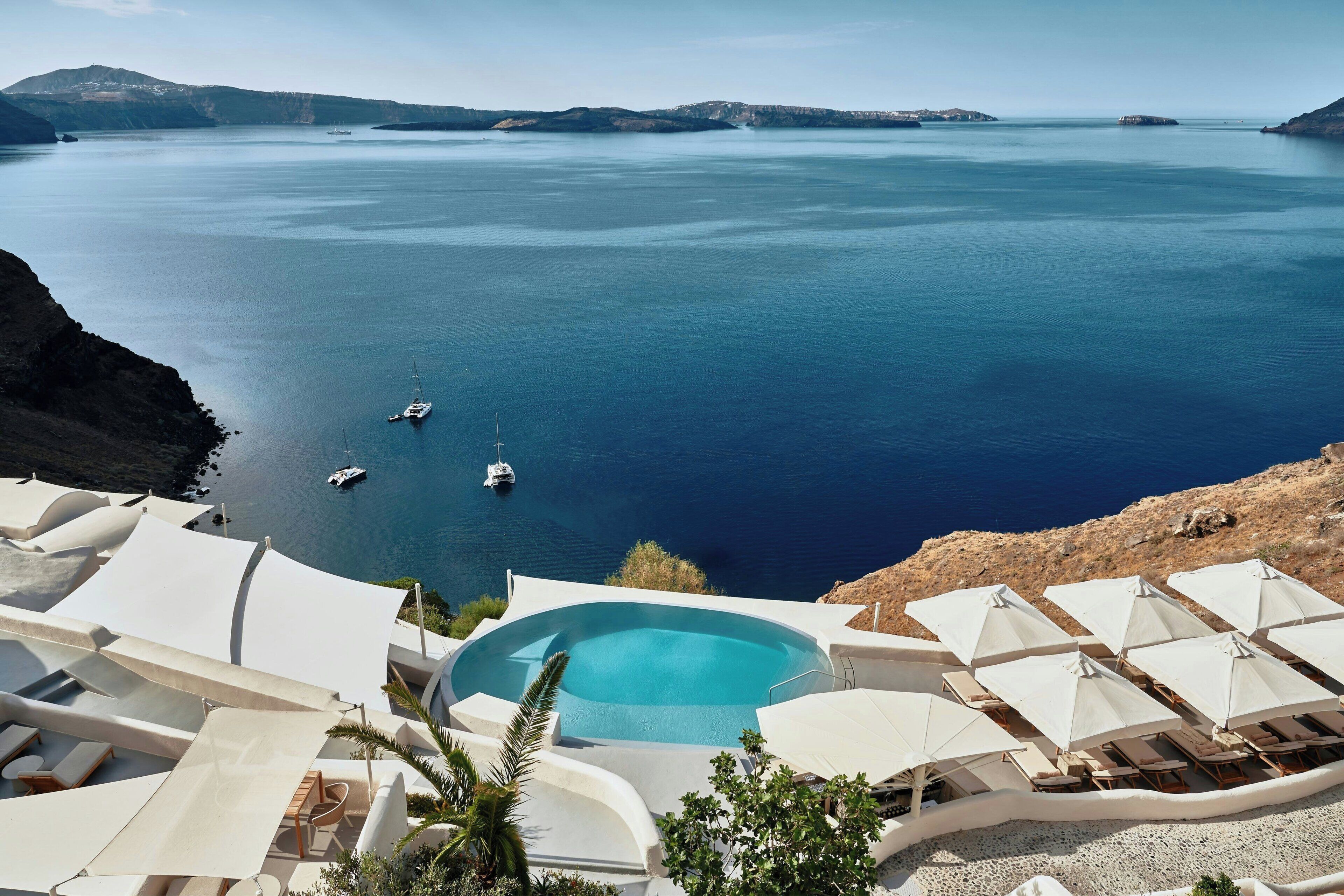 Un resort con piscina, tumbonas, sombrillas y vistas al mar.
