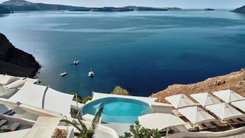 Un resort con piscina, tumbonas, sombrillas y vistas al mar.