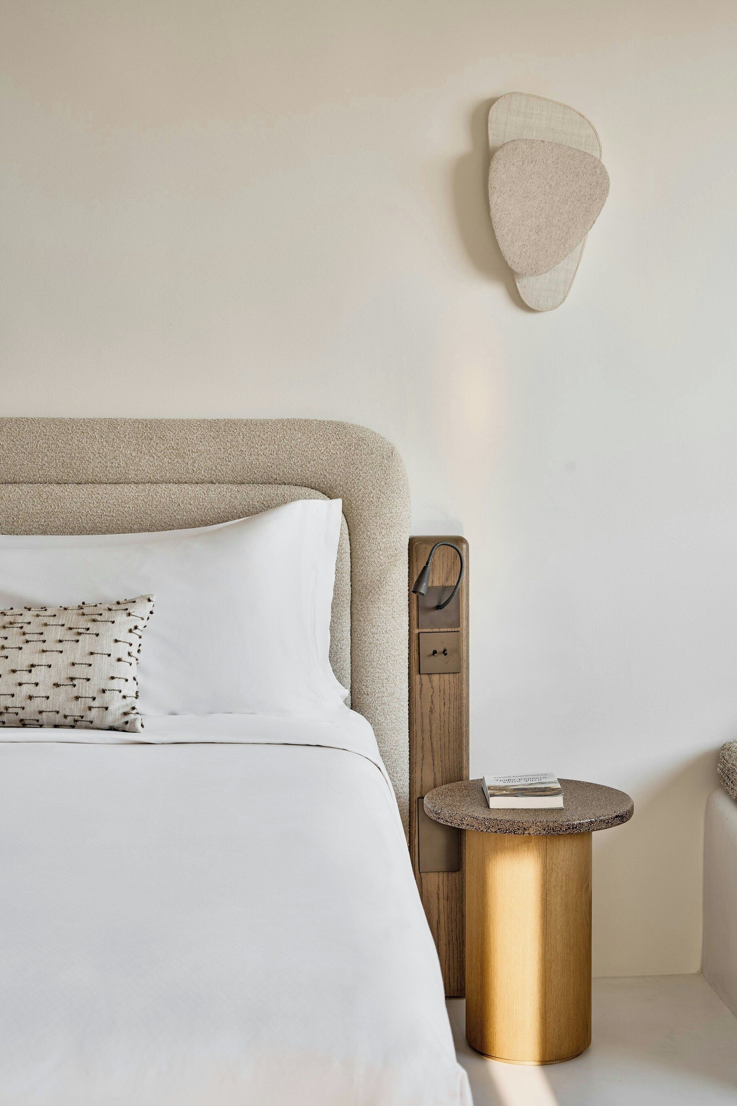 A bedroom with a bed, a round side table, and a wall-mounted object.