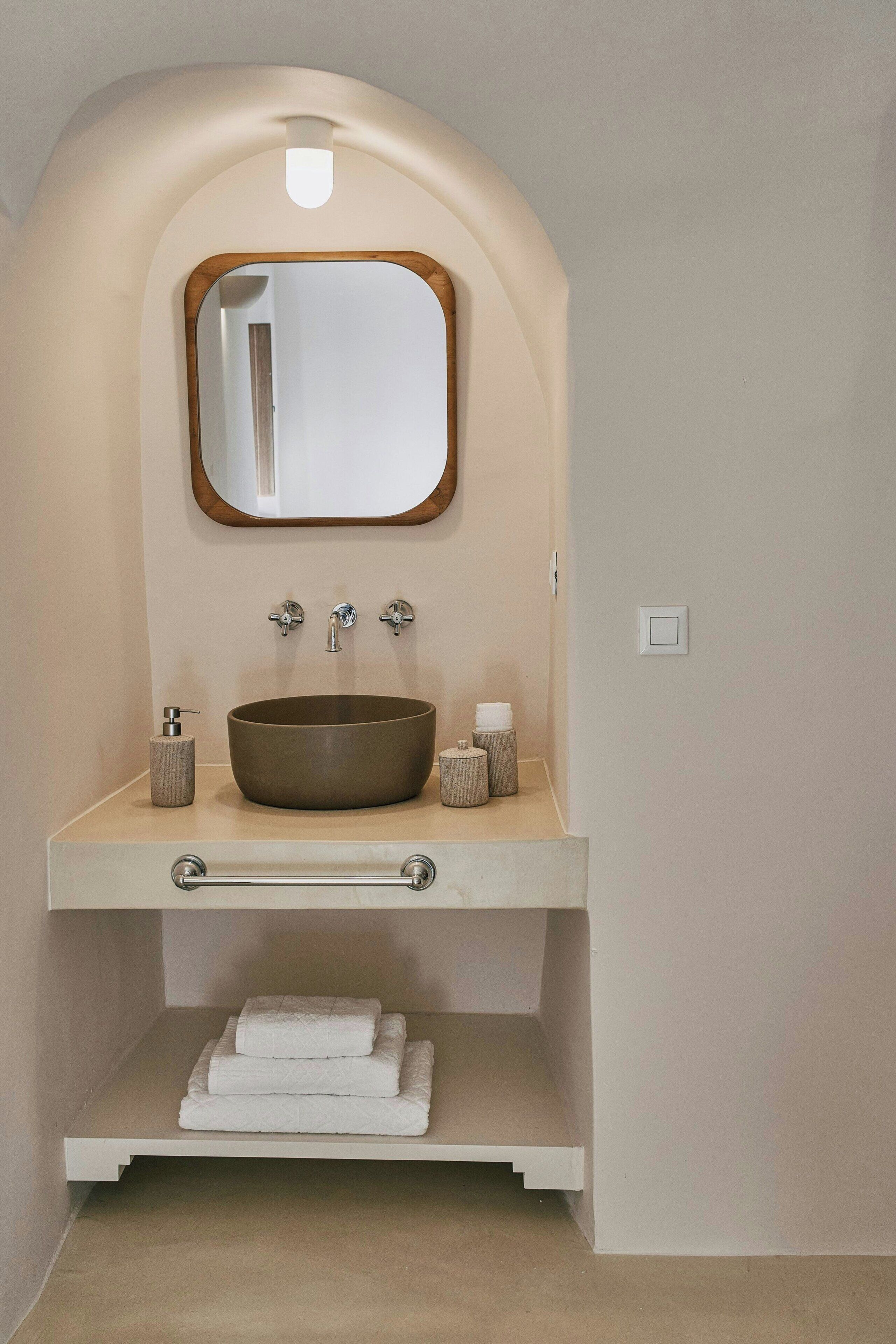 A bathroom with a freestanding sink, a mirror, and a towel rack.