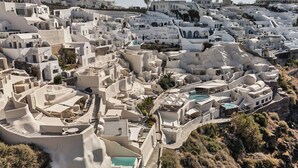 A white-washed village with terraced buildings, a central pool, and a winding road. - Mystique, a Luxury Collection Hotel, Santorini (Santorini)