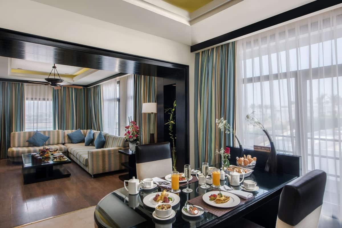 A hotel room with a dining area, a sofa, and a view of the outdoors.