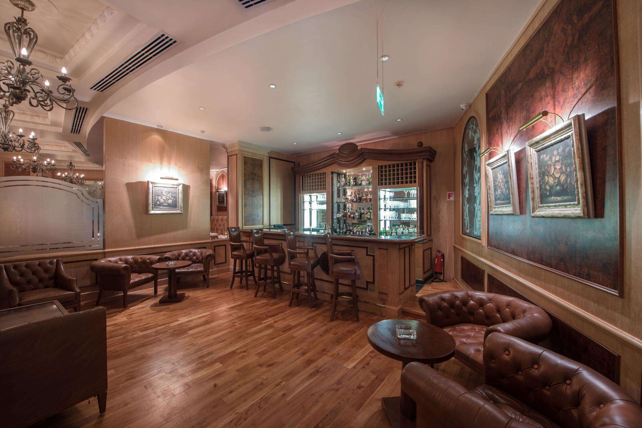 A bar area with wooden flooring, leather seating, and a bar counter.