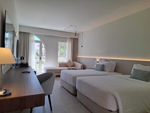 Une chambre d’hôtel équipée d’un bureau, de deux lits, d’une chaise, d’une lampe et offrant une vue sur l’extérieur.