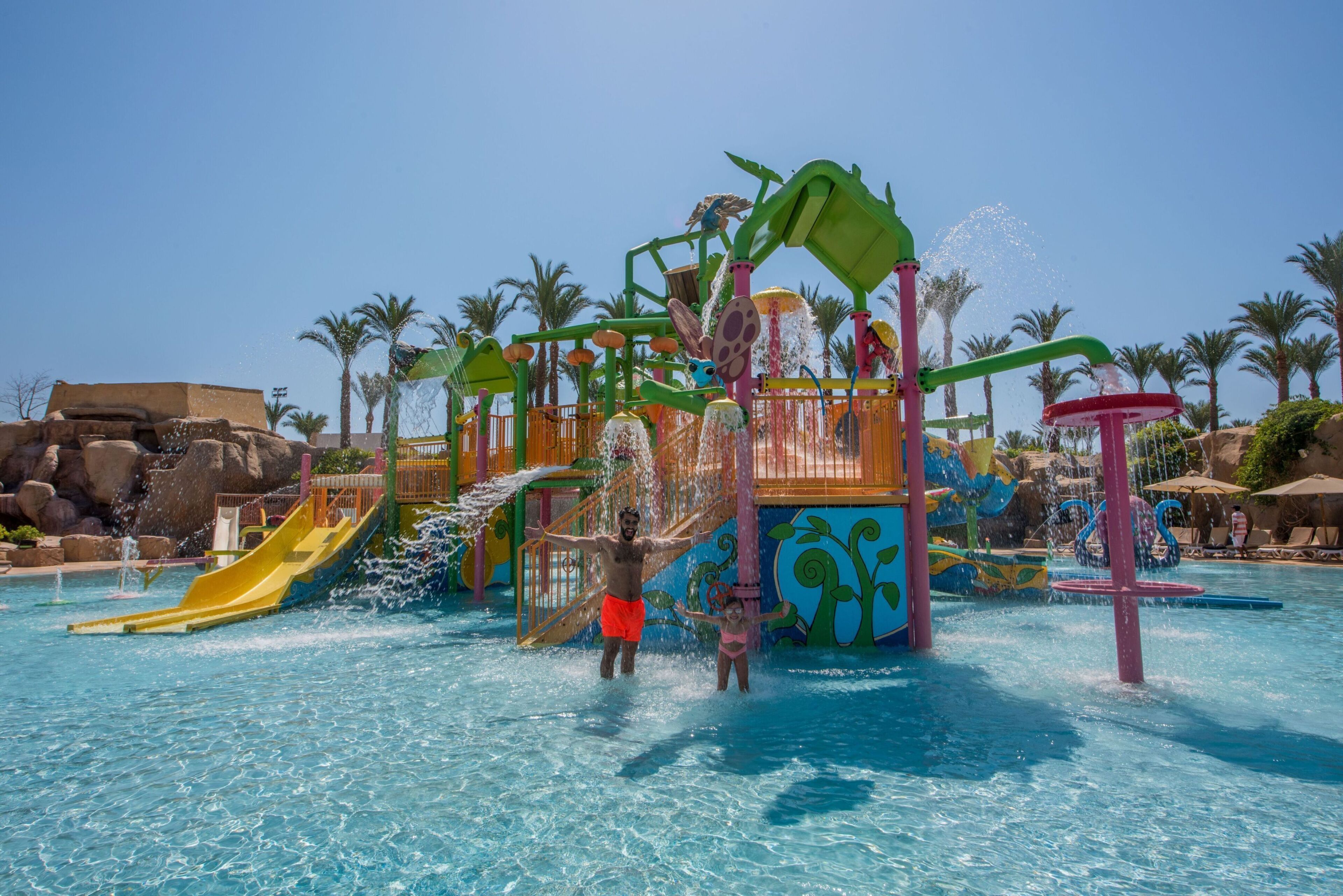 A water park with slides, water features, and palm trees.