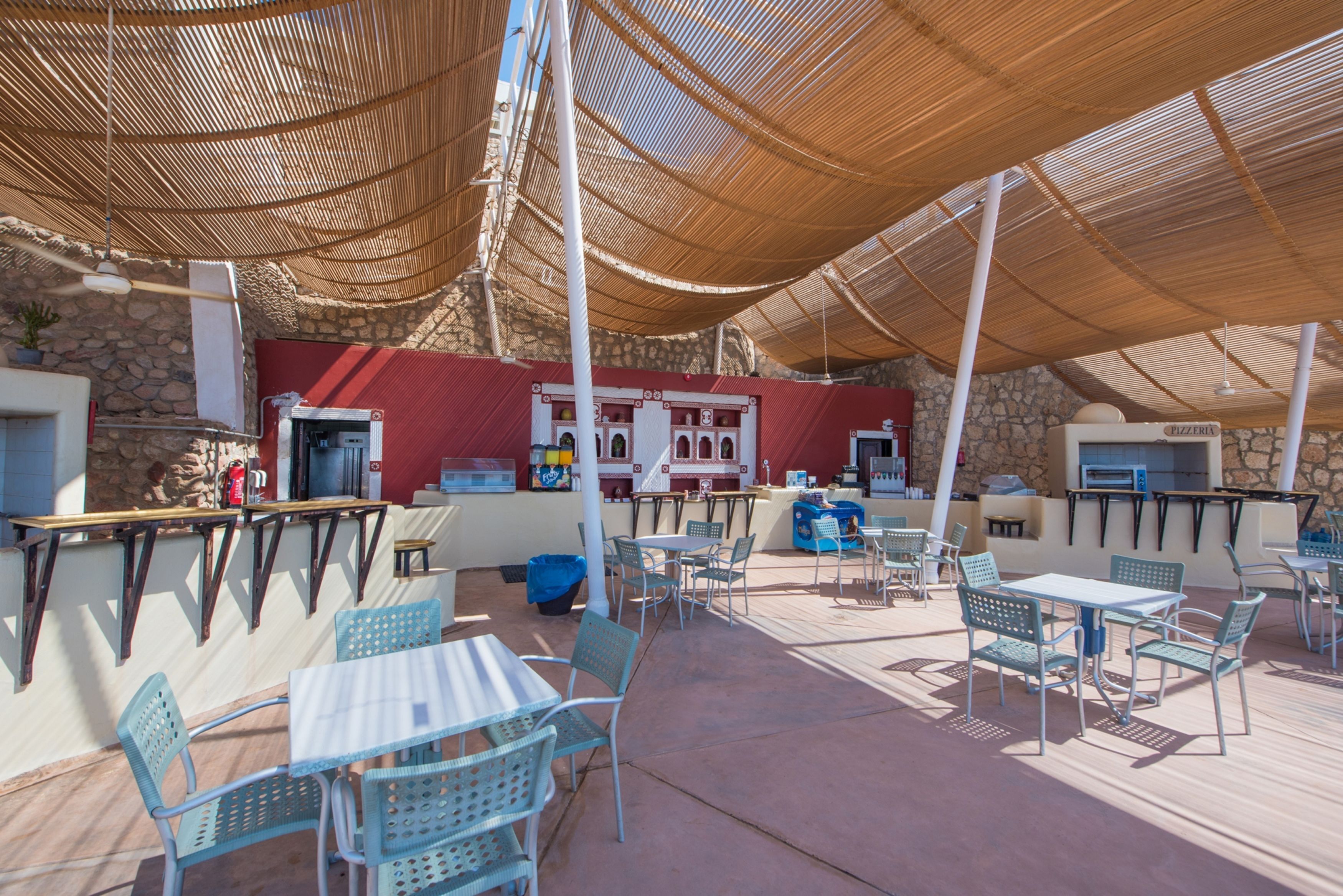 An outdoor patio area with tables and chairs, a stone wall, and a pizzeria sign.