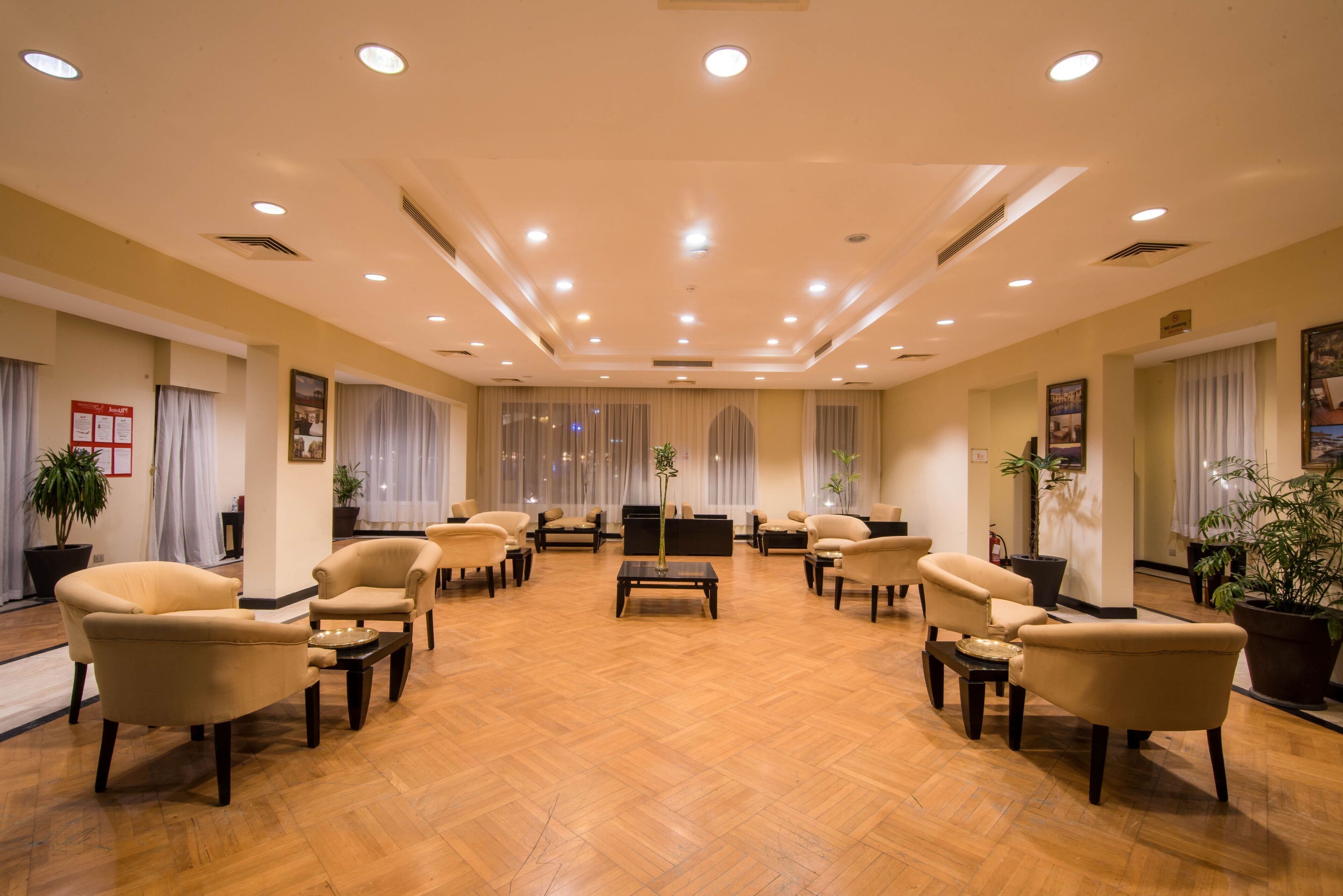 Um hall amplo com várias áreas de estar, uma mesa de centro e uma televisão.