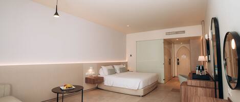 Una habitación de hotel moderna con una cama, mesita de noche y una pequeña mesa redonda con una lámpara.