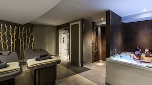 A modern spa room with a large bathtub, two massage tables, and a glass shower enclosure. - Langdale Hotel  (Ambleside)
