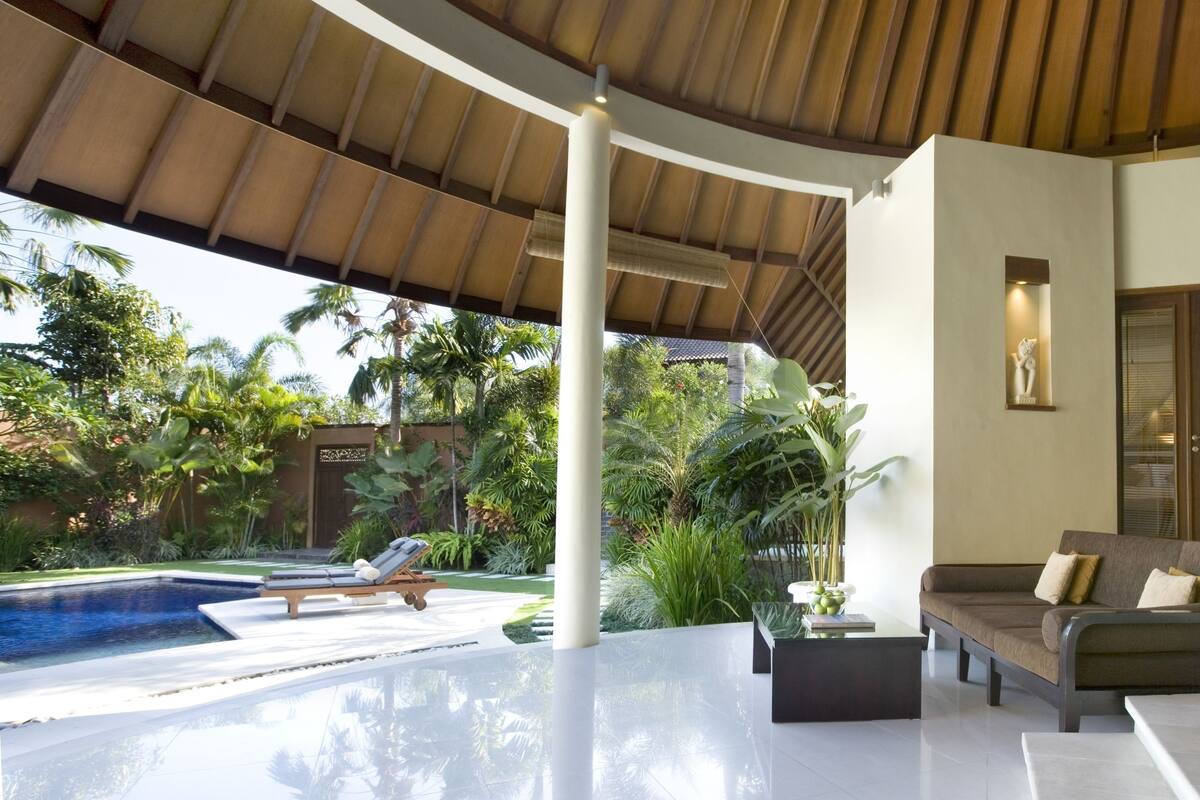 A modern outdoor living area with a pool, a sofa, and a coffee table.