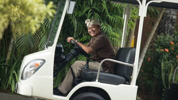 A golf cart with a driver, surrounded by lush greenery.