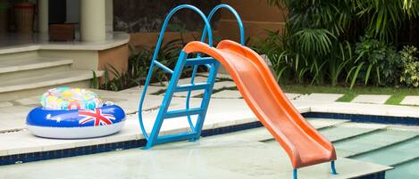 A swimming pool with a slide and inflatable rings.