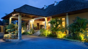 A modern building with a covered entrance, steps leading to the main door, and lush tropical landscaping. - The Kunja (Seminyak)