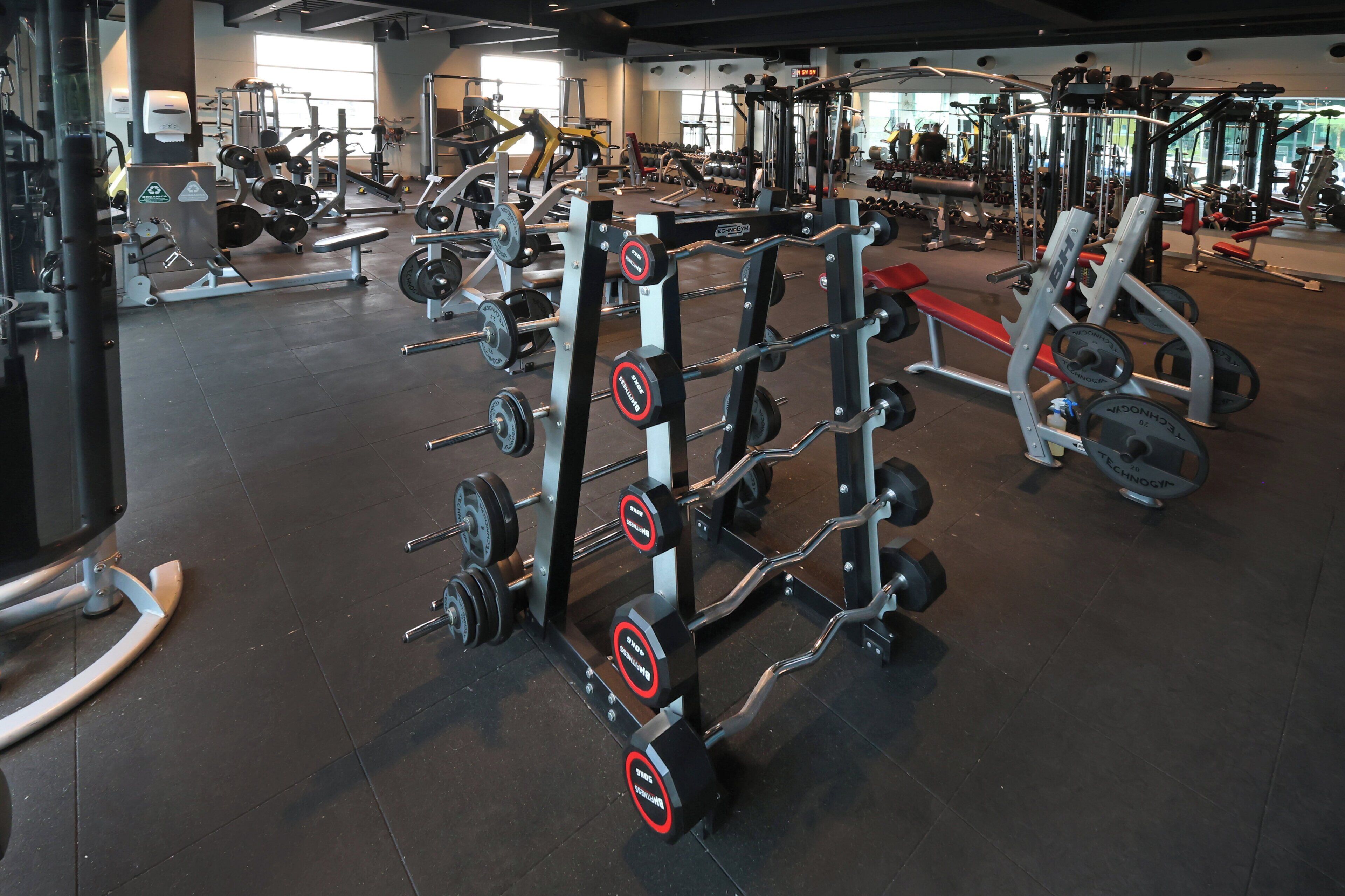 A gym with various weightlifting equipment, benches, and dumbbells.