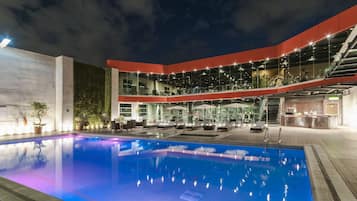 Relax by the pool surrounded by lounge chairs and umbrellas in a shaded seating area.