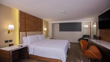 Ein Hotelzimmer mit Bett, Schreibtisch, Stuhl und einem großen Spiegel.