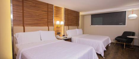 Una habitación de hotel con dos camas, un escritorio con lámpara, una silla y un ventanal.
